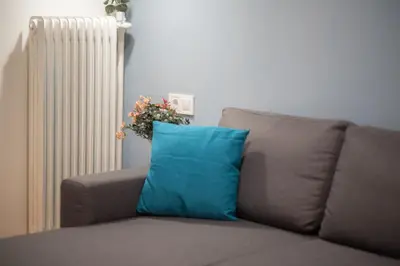 a couch with a blue pillow next to a radiator at Dream Apt in Ampelokipoi in Athens