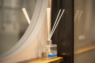 a bottle with two candles sitting on a table in front of a mirror at Dream Apt in Ampelokipoi in Athens