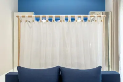 a white curtain in a room with a blue couch at EstelZan Apartment in Athens