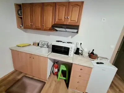 a small kitchen with wooden cabinets and a stove at West Athens Welcome Δυτικά της Αθήνας in Athens