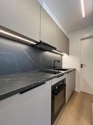 a kitchen with white cabinets and a black counter top at BlueMotion - CruiseNest Complex in Piraeus