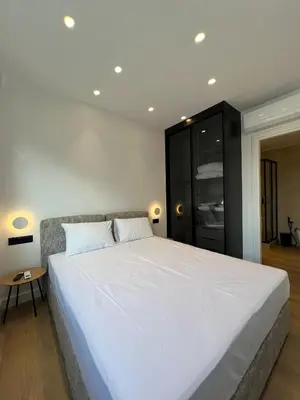 a bedroom with a large white bed and a black cabinet at BlueMotion - CruiseNest Complex in Piraeus