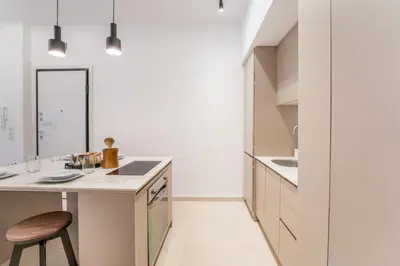 a white kitchen with a counter and a stool at Secret Central Gem Near Kolonaki in Athens