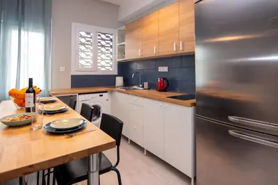 a kitchen with a wooden table and a stainless steel refrigerator at Nice Apartment in Athens center in Athens