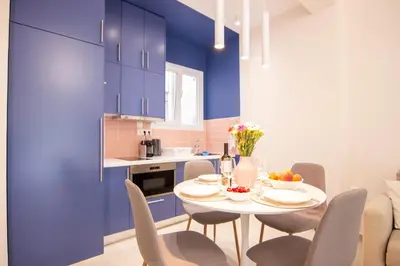 a kitchen with blue cabinets and a white table and chairs at Apartment near Onassis cultural center in Athens