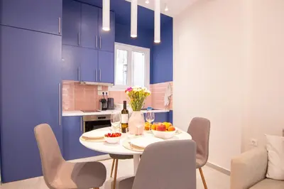 a dining room with blue cabinets and a white table and chairs at Apartment near Onassis cultural center in Athens