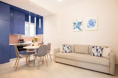 a living room with a couch and a table and chairs at Apartment near Onassis cultural center in Athens