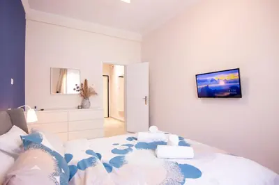 a white bedroom with a bed and a bathroom at Apartment near Onassis cultural center in Athens