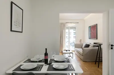 a white living room with a table with a bottle of wine at Athens Acropolis Residence, by the Acropolis Museum in Athens