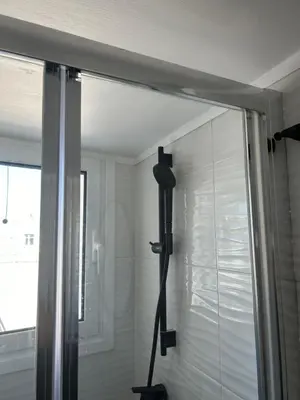 a glass shower door in a bathroom next to a window at Cozy apartment in lycabettus hills in Athens