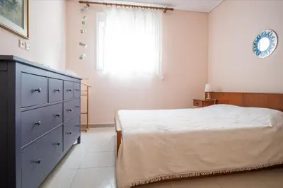 a bedroom with a bed and a dresser and a window at Family home in Lagonisi in Lagonissi