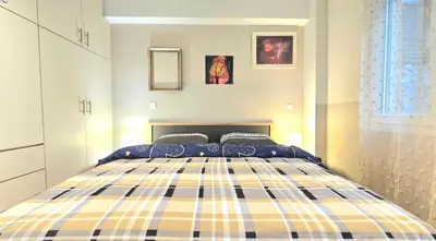 a bedroom with a yellow and blue plaid bed at Όμορφο ημιυπόγειο διαμέρισμα στην Αθήνα με αυλή in Athens