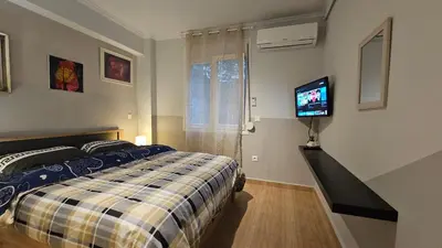 a bedroom with a bed and a flat screen tv at Όμορφο ημιυπόγειο διαμέρισμα στην Αθήνα με αυλή in Athens