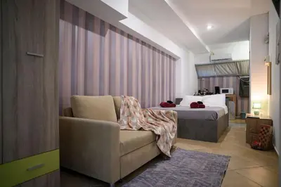 a bedroom with a bed and a couch and a chair at Premium Athenian District Urban Studio in Athens