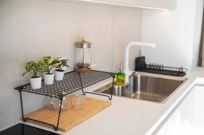 a kitchen counter with a sink and a shelf with plants at Oculus Kallithea Creators Hub&Suite by Live&Travel in Athens