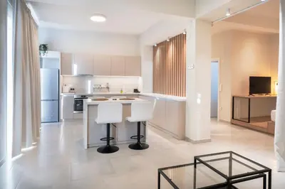 a kitchen with a counter and two white stools at Oculus Kallithea Creators Hub&Suite by Live&Travel in Athens