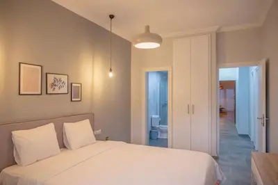 a bedroom with a white bed and a bathroom at Fresh&comfy4family & friends in Athens