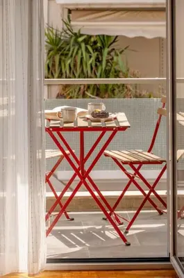 a red table and a chair on a porch at Fresh&comfy4family & friends in Athens
