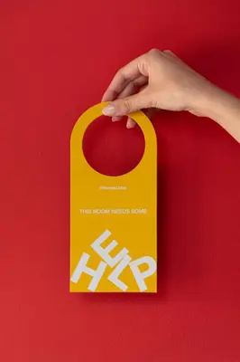 a hand holding a yellow object on a red background at Fits Living in Athens