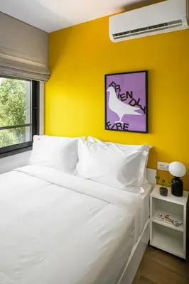 a bedroom with a white bed with a yellow wall at Fits Living in Athens