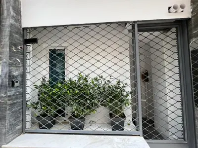 a plant behind a fence in front of a door at Ground floor appartment Panormou Metro in Athens