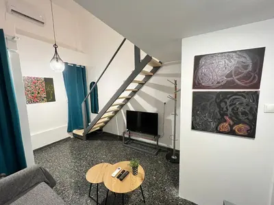 a living room with a table and a staircase at Ground floor appartment Panormou Metro in Athens