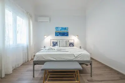 a white bedroom with a bed and a stool at Peaceful and comfy 2BA in Athens heart in Athens