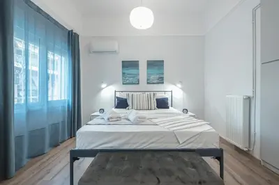 a white bedroom with a large bed and a large window at Peaceful and comfy 2BA in Athens heart in Athens