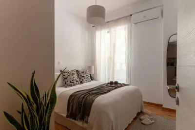 a white bedroom with a bed and a plant at Renovated Gem near Pedion Areos Park & Museums in Athens