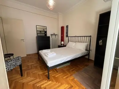 a bedroom with a white bed and a wooden floor at Downtown Pagrati Modern Apartment in Athens