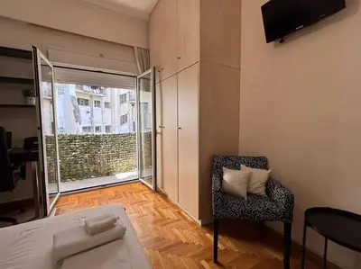 a living room with a chair and a large window at Downtown Pagrati Modern Apartment in Athens