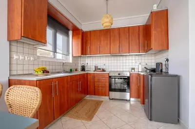a kitchen with wooden cabinets and a stainless steel refrigerator at Luxury apt near the airport N2 in Spáta