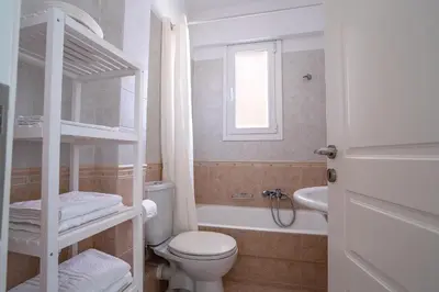 a white bathroom with a toilet and a sink at Luxury apt near the airport N2 in Spáta
