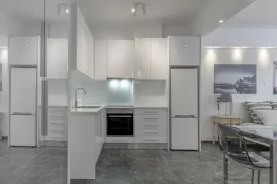 a kitchen with white cabinets and a table and a couch at Central Studio in Athens lower Pangrati 650m Evangelismo Metro in Athens