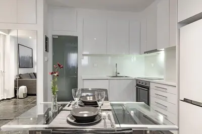a white kitchen with a table with plates and wine glasses at Central Studio in Athens lower Pangrati 650m Evangelismo Metro in Athens