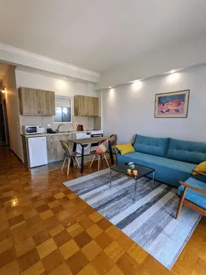 a living room with a blue couch and a kitchen at Cozy Corner, One-Bedroom Flat in Athens