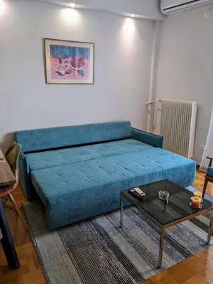 a blue couch in a living room with a table at Cozy Corner, One-Bedroom Flat in Athens
