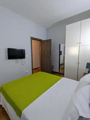a bedroom with a white bed with a green blanket at Cozy Corner, One-Bedroom Flat in Athens
