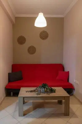 a red couch in a living room with a table at Penthouse with Acropolis view in Attiki Metro in Athens