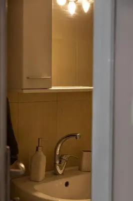 a bathroom with a sink with a mirror and a soap dispenser at Penthouse with Acropolis view in Attiki Metro in Athens