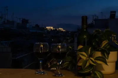 two wine glasses sitting on a table with a bottle of wine at Penthouse with Acropolis view in Attiki Metro in Athens