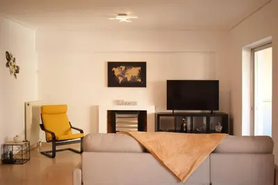 a living room with a couch and a tv and a chair at Enjoy The Athens Riviera! in Athens