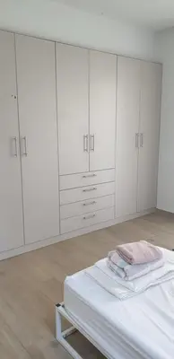 a white bedroom with white cabinets and a bed at Al Fresco Voula Apartment in Athens