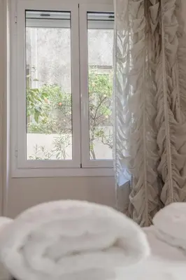 a bedroom with a window and a white curtain at 1 BD Lycabettus Neoclassic House by Live&Travel in Athens