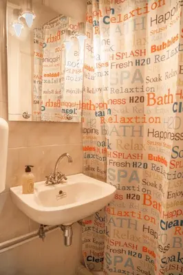 a bathroom with a sink and a shower curtain at 1 BD Lycabettus Neoclassic House by Live&Travel in Athens