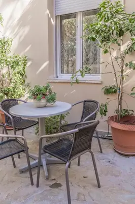 a table and chairs on a patio with potted plants at 1 BD Lycabettus Neoclassic House by Live&Travel in Athens
