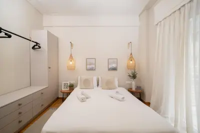 a white bedroom with a large white bed and a window at Meraki Koukaki by A&D Properties in Athens