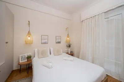 a white bedroom with a white bed and a window at Meraki Koukaki by A&D Properties in Athens