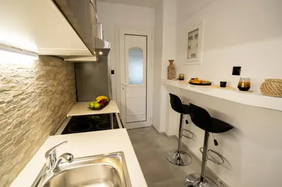 a kitchen with a sink and two stools at V Suites - Apts & Spa in Athens