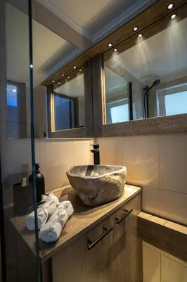 a bathroom with a stone sink and mirrors at V Suites - Apts & Spa in Athens